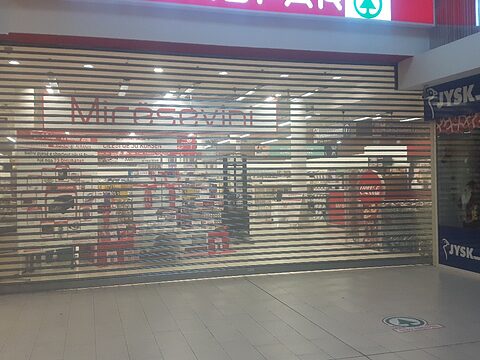 Mesh rolling shutter closed at night with the shop visible through it