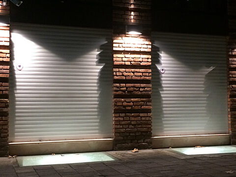 Rolling shutter closed at night, lit by facade lamps